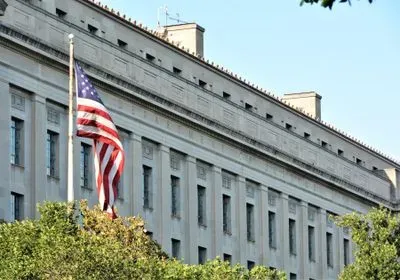 photograph of an american flag in front of the department of justice building